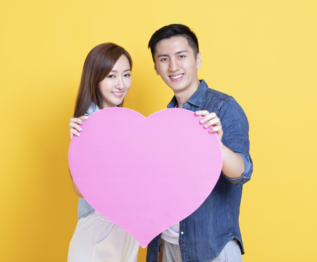 smiling young couple showing pink heart shape  signの写真素材