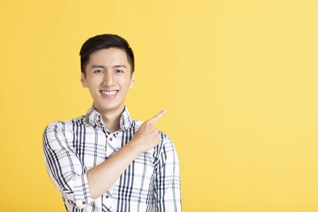 Handsome young man pointing right with his fingerの写真素材