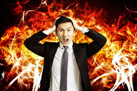 angry young business man with burning fire background