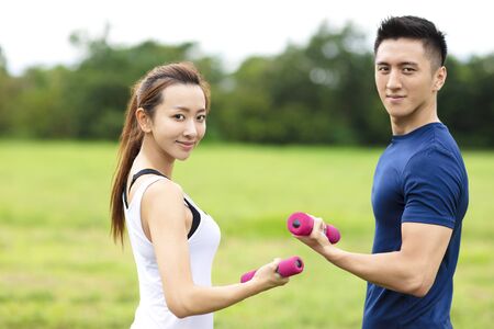 asian young couple training with dumbbellsの写真素材