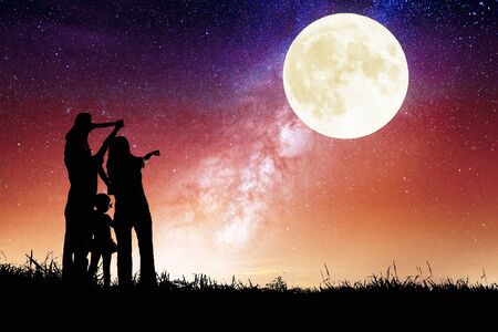 Family standing on hill and watching the moon. Celebrate Mid-autumn festival togetherの写真素材