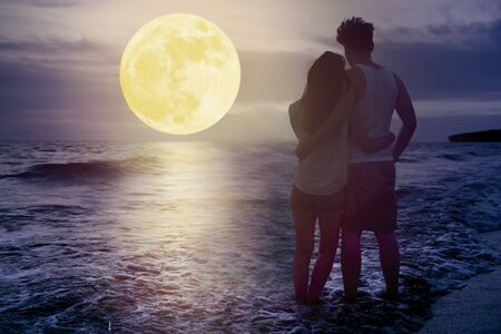 couple standing on beach and watching the moon. Celebrate Mid autumn festival togetherの写真素材