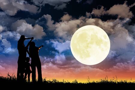 Family standing on hill and watching the moon. Celebrate Mid-autumn festival togetherの写真素材