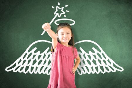 little girl standing against chalkboard and magic   conceptの写真素材