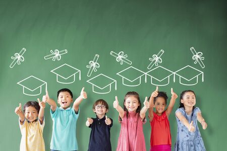 happy Multi-ethnic group of school children standing in classroom with graduation conceptの写真素材