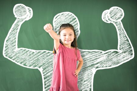 little girl standing against chalkboard and strong winner concept