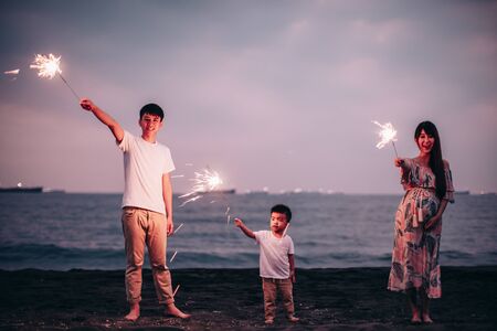 happy family celebrating new year with sparklers  on the beach