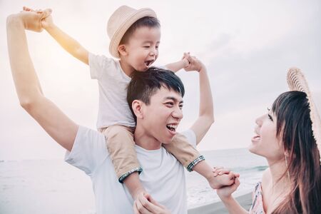 happy asian family playing on the beach at sunsetの写真素材