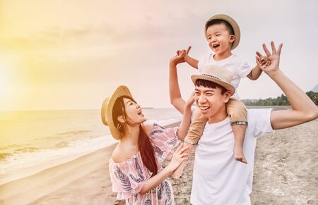happy asian family playing on the beach at sunsetの写真素材