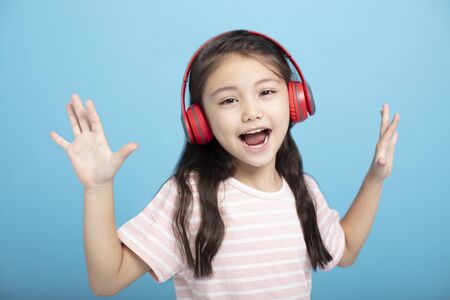 happy little girl with headphones listening and singing song
