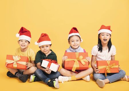 Group of happy kids in Christmas hat with presents