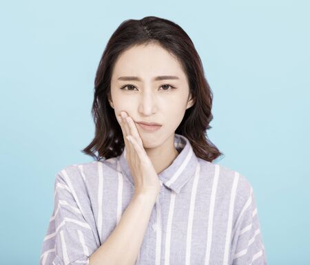 young woman touching mouth with hand with painful expressionの写真素材