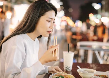 Asian woman enjoy bubble milk tea with street food in  Night Market