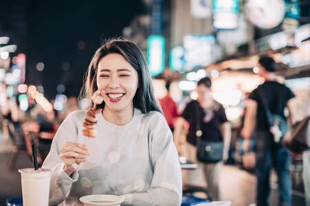 Asian young woman enjoy  street food in  Night Marketの写真素材
