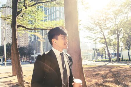 Businessman holding mobile phone while walking on street to officeの写真素材