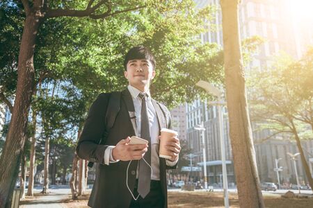 Businessman holding mobile phone while walking on street to office