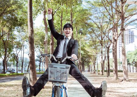 happy Businessman riding bicycle to work on urban streetの写真素材