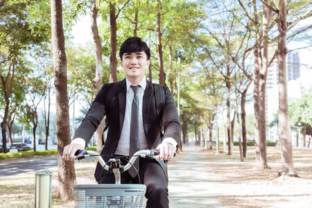 Businessman riding bicycle to work on urban street at morningの写真素材