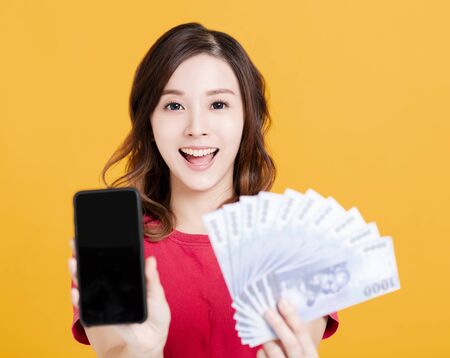 happy young woman holding mobile phone and money.の写真素材