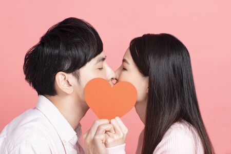 Happy young couple  holding red paper hearts and kissingの写真素材