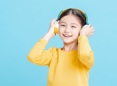 Happy little girl   listens to music in headphones