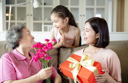 Happy mother's day  . Child and  mother congratulating grandmother  giving her flowers and  gift boxの写真素材