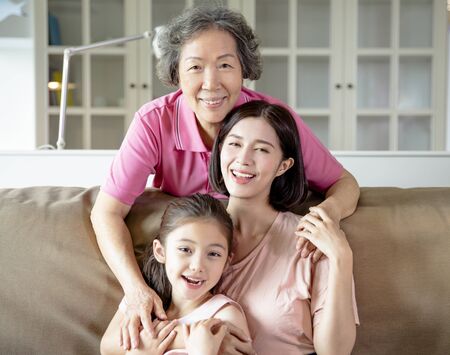 happy grandmother and daughter with granddaughter at homeの写真素材