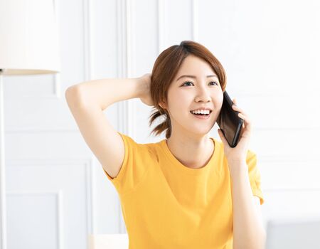 smiling young Woman talking on the phone at homeの写真素材