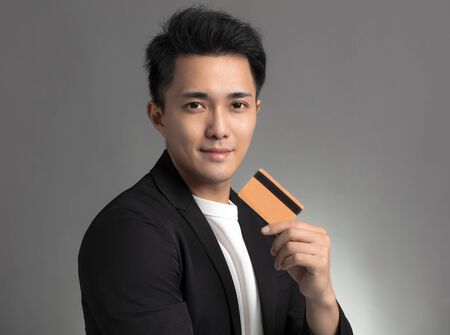 young asian business man showing credit card isolated over gray background