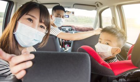 asian family with children rides in their car and wear medical masksの写真素材