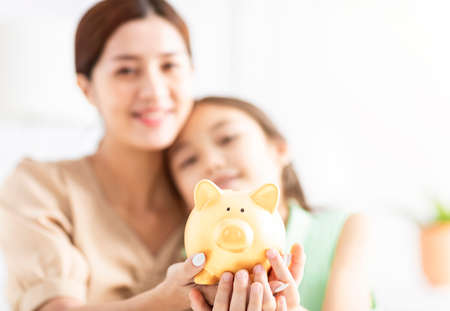 Mother and her daughter holding piggy bankの写真素材