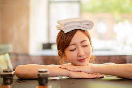 Asian Young woman relaxing and massaging in hot springの写真素材