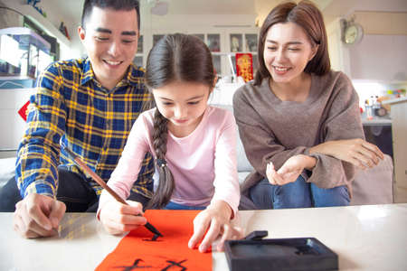 happy chinese new year. surprised parent and child watching the red envelope with money. chinese text: spring timeの写真素材