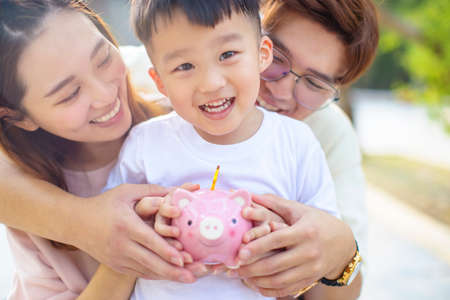 happy parent holding piggy bank and teaching son save moneyの写真素材