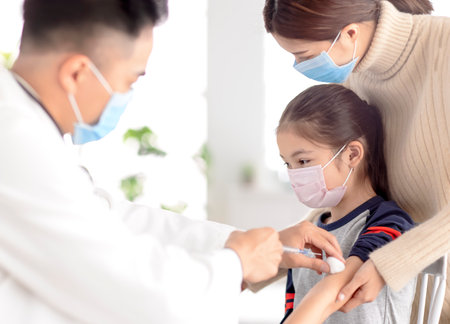 doctor examining kid and giving injection. Coronavirus vaccination and Covid-19 vaccine conceptの写真素材