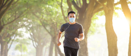 young man in face mask and running in the parkの写真素材