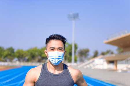 Man in medical mask and running on the trackの写真素材