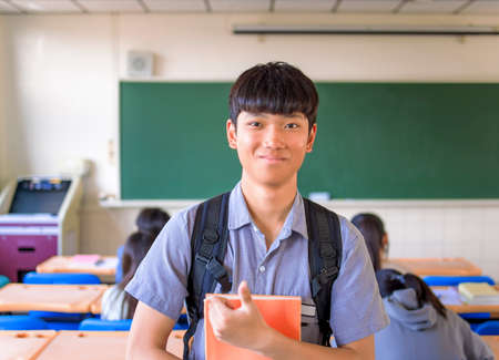 Smiling asian student teenager boy in classroomの写真素材