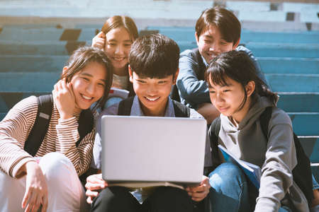 young students wearing with face masks and sitting on the stairsの写真素材