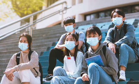young students wearing with face masks and sitting on the stairsの写真素材