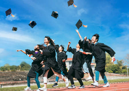 Happy Students with congratulations throwing graduation hats in the air for celebratingの写真素材