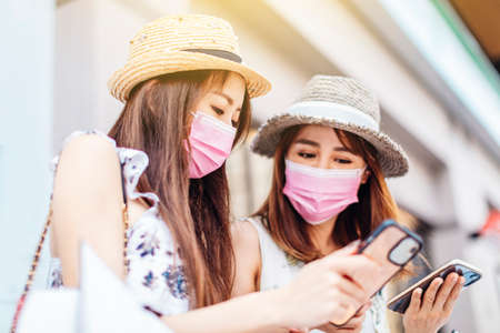 young woman wearing face protective medical mask and holding shopping bags on the streetの写真素材