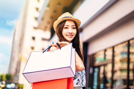 Happy young woman holding shopping bags on the streetの写真素材
