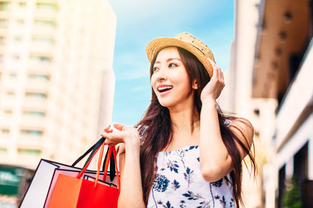 Happy young woman holding shopping bags on the streetの写真素材