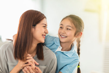 Happy daughter and mother listening music with headphones at homeの写真素材