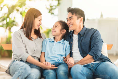 Happy family smiling and hugging on the couch at homeの写真素材