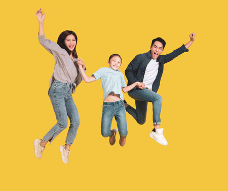Happy young family with one child jumping togetherの写真素材