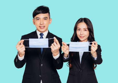 young asian business man and woman wearing mask looking at camera