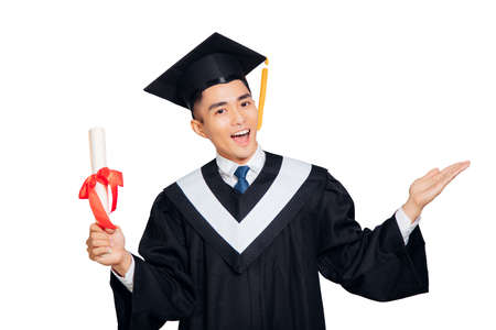 young man in black graduation gown and cap holding a diploma isolated on white backgroundの写真素材
