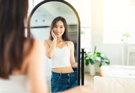 young woman confidently measured her waist circumference, satisfied with her posture, and very happy to lose weightの写真素材